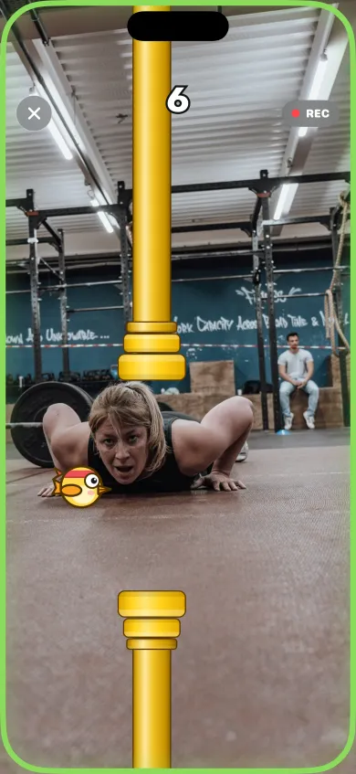 Live game in a gym: a woman mid push-up with the bird passing a yellow pipe and a score of 6
